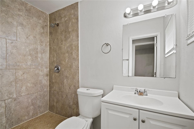 bathroom featuring a tile shower, vanity, and toilet