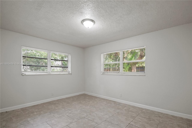 tiled empty room featuring a textured ceiling