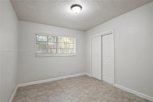 unfurnished bedroom featuring light tile patterned floors, a textured ceiling, and a closet