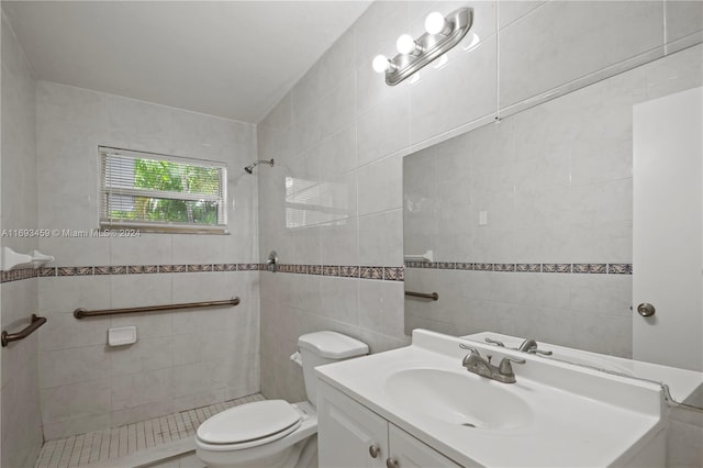 bathroom featuring tiled shower, toilet, tile walls, and vanity