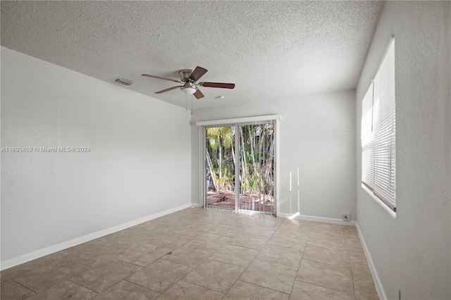 empty room featuring light tile patterned floors, a textured ceiling, and ceiling fan