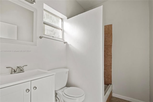 bathroom with a tile shower, vanity, and toilet