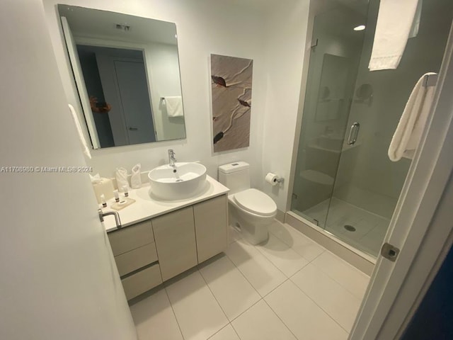 bathroom featuring tile patterned floors, vanity, toilet, and a shower with door