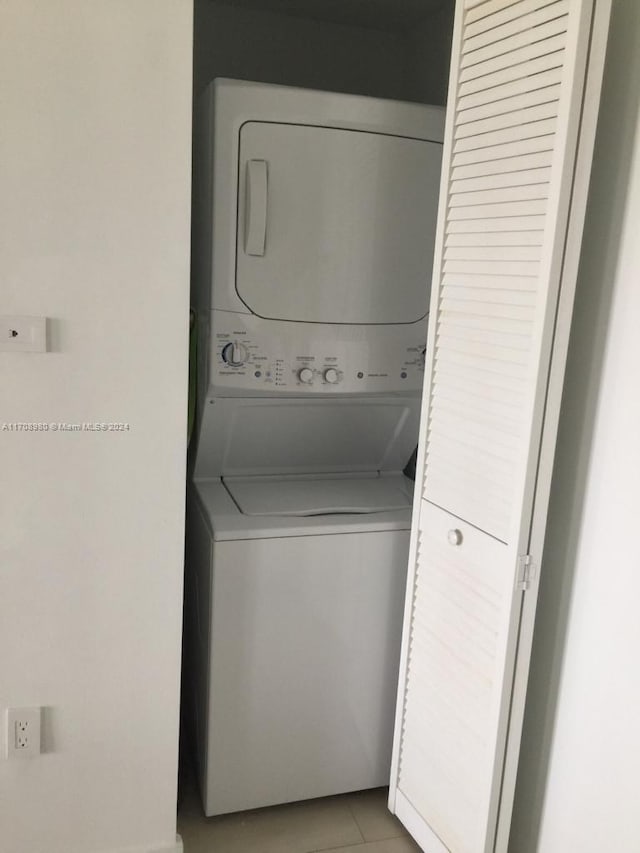 laundry room with light tile patterned flooring and stacked washer and clothes dryer