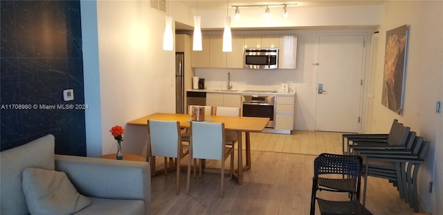 kitchen featuring sink, stainless steel appliances, a kitchen breakfast bar, light hardwood / wood-style flooring, and decorative light fixtures