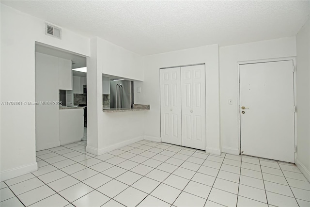 unfurnished living room featuring light tile patterned flooring and a textured ceiling