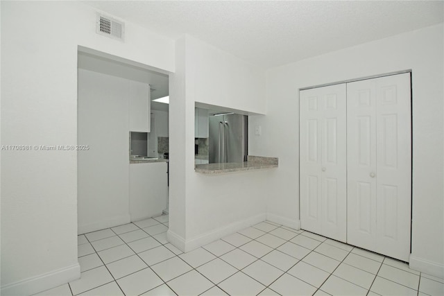 interior space featuring light tile patterned floors and a textured ceiling