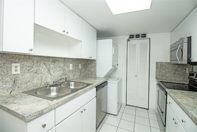 kitchen featuring stacked washing maching and dryer, stainless steel appliances, white cabinets, and sink