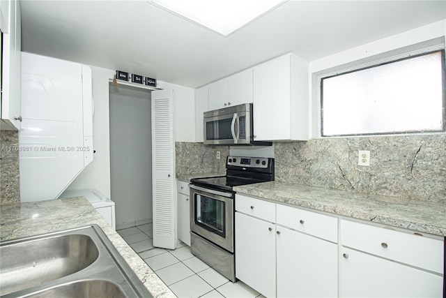 kitchen with appliances with stainless steel finishes, tasteful backsplash, sink, white cabinetry, and light tile patterned flooring