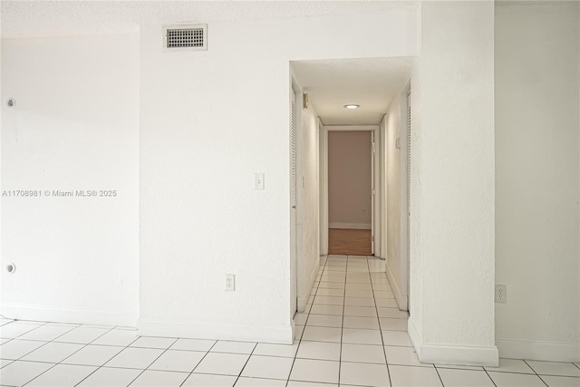 corridor with light tile patterned floors and a textured ceiling