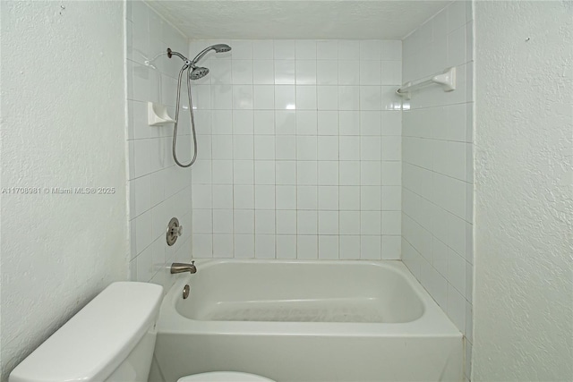 bathroom featuring tiled shower / bath combo and toilet