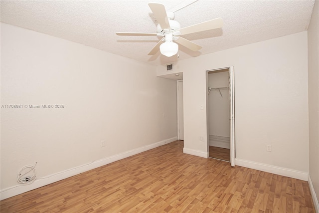 unfurnished bedroom with ceiling fan, light wood-type flooring, a textured ceiling, and a closet