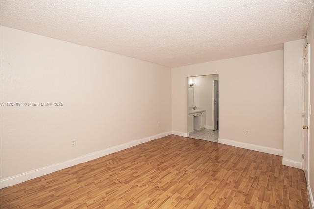 empty room featuring a textured ceiling and light hardwood / wood-style flooring