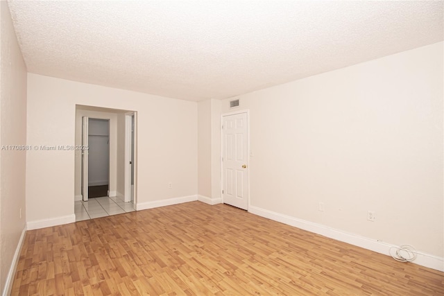 spare room featuring a textured ceiling and light wood-type flooring