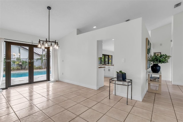 empty room with light tile patterned flooring, vaulted ceiling, and an inviting chandelier