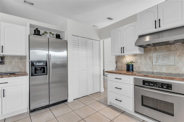 kitchen with white cabinets, light tile patterned floors, backsplash, and appliances with stainless steel finishes