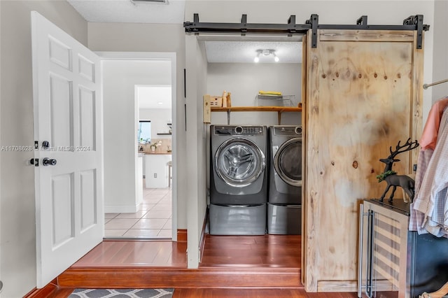 laundry area featuring beverage cooler, a barn door, separate washer and dryer, a textured ceiling, and hardwood / wood-style flooring