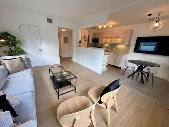 living room with sink, a notable chandelier, and light wood-type flooring