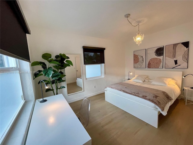 bedroom with multiple windows, hardwood / wood-style floors, and an inviting chandelier