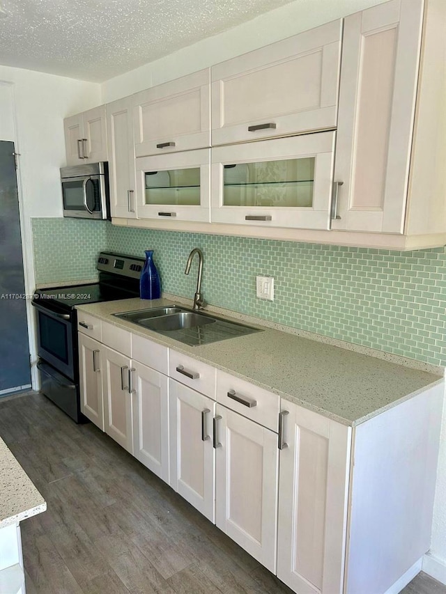 kitchen with sink, electric range oven, wood-type flooring, decorative backsplash, and white cabinets