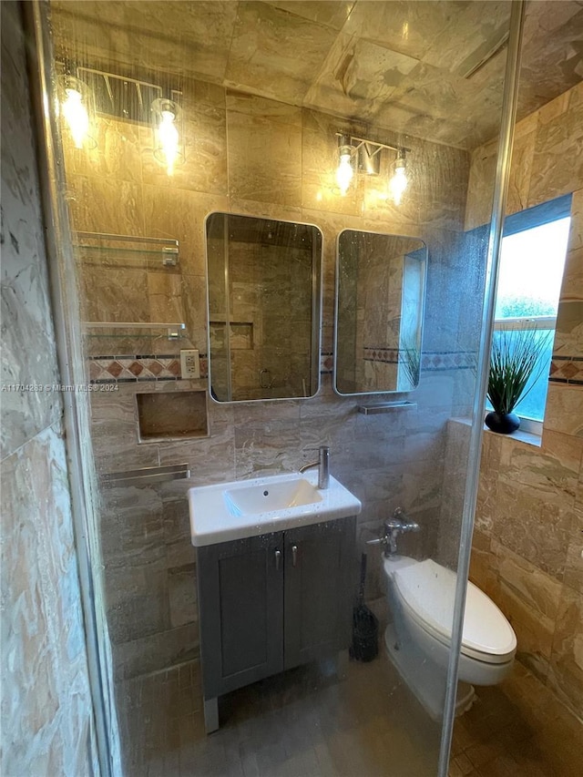 bathroom with a bidet, vanity, tile walls, and toilet