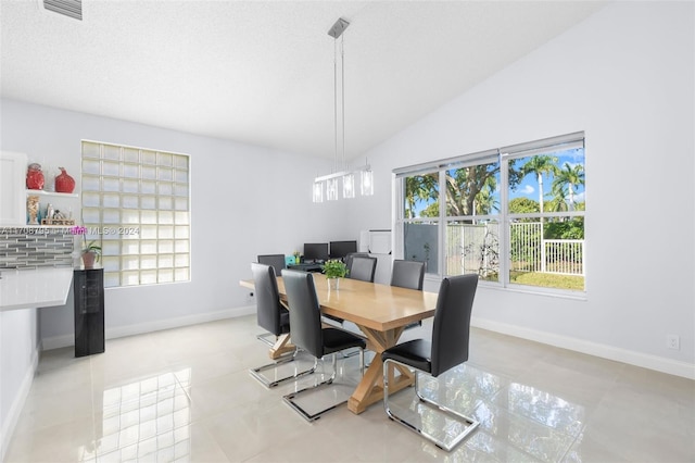 dining area featuring light tile patterned floors, a textured ceiling, and vaulted ceiling