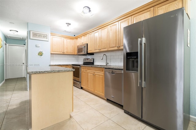 kitchen with appliances with stainless steel finishes, backsplash, light stone counters, sink, and light tile patterned floors