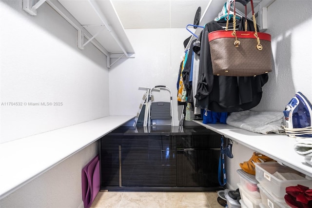 walk in closet with light tile patterned floors