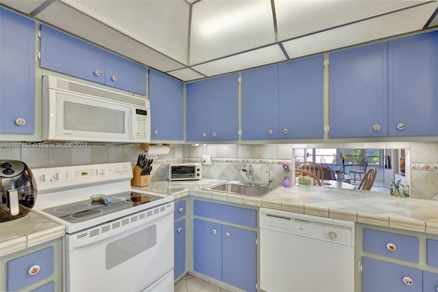 kitchen with tile countertops, sink, white appliances, and blue cabinets