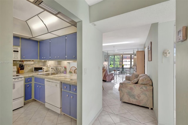 kitchen featuring white appliances, tasteful backsplash, blue cabinets, and tile counters