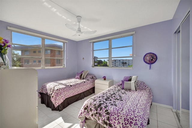 tiled bedroom with multiple windows, ceiling fan, and a closet