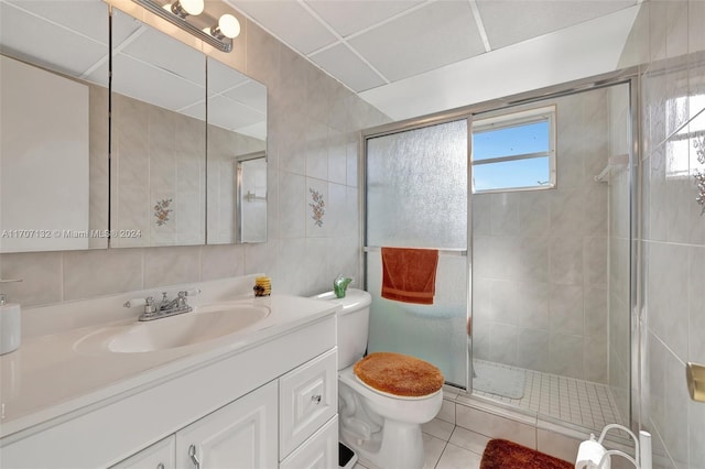 bathroom featuring vanity, tile patterned flooring, toilet, tile walls, and an enclosed shower