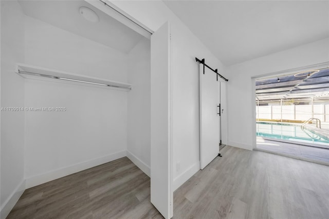 hallway featuring a barn door and light hardwood / wood-style flooring