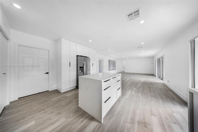 kitchen with stainless steel fridge with ice dispenser, white cabinetry, light hardwood / wood-style flooring, and a kitchen island