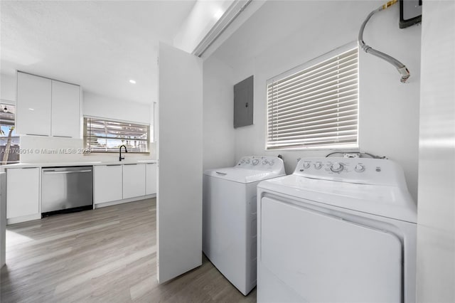 laundry area featuring washer and dryer, sink, electric panel, and light hardwood / wood-style flooring