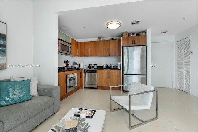 300 S Biscayne Blvd Unit T-2309, Miami, FL 33131 - kitchen featuring appliances with stainless steel finishes, dark countertops, brown cabinetry, light tile patterned floors, and open floor plan