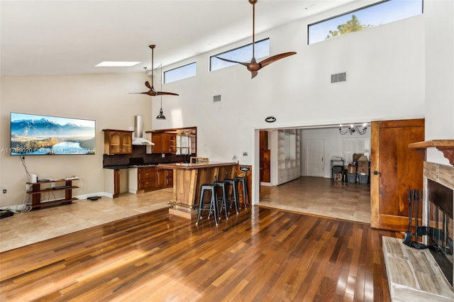 living room featuring ceiling fan, a wealth of natural light, a high ceiling, and a skylight