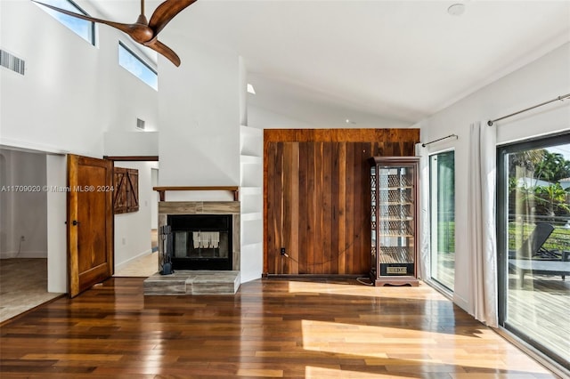 unfurnished living room featuring a multi sided fireplace, dark hardwood / wood-style flooring, ceiling fan, and a healthy amount of sunlight