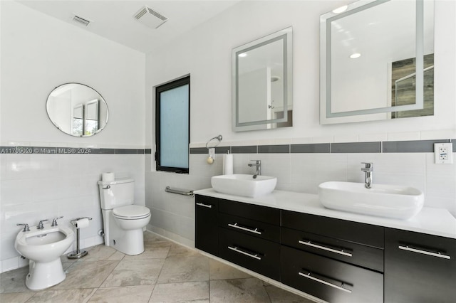 bathroom with vanity, toilet, tile walls, and a bidet