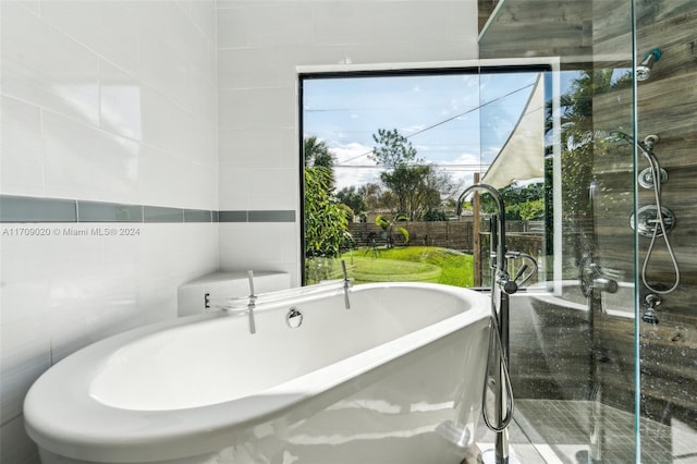 bathroom with plenty of natural light, shower with separate bathtub, and tile walls