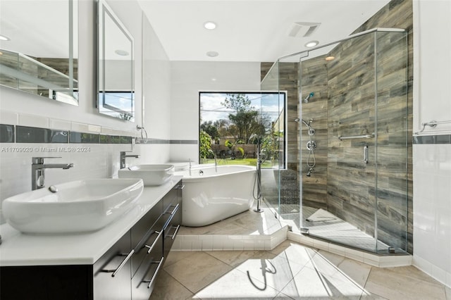 bathroom with tile patterned flooring, shower with separate bathtub, vanity, and tile walls