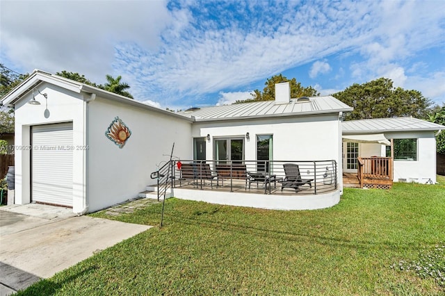 rear view of house featuring a lawn, a garage, an outbuilding, and a patio