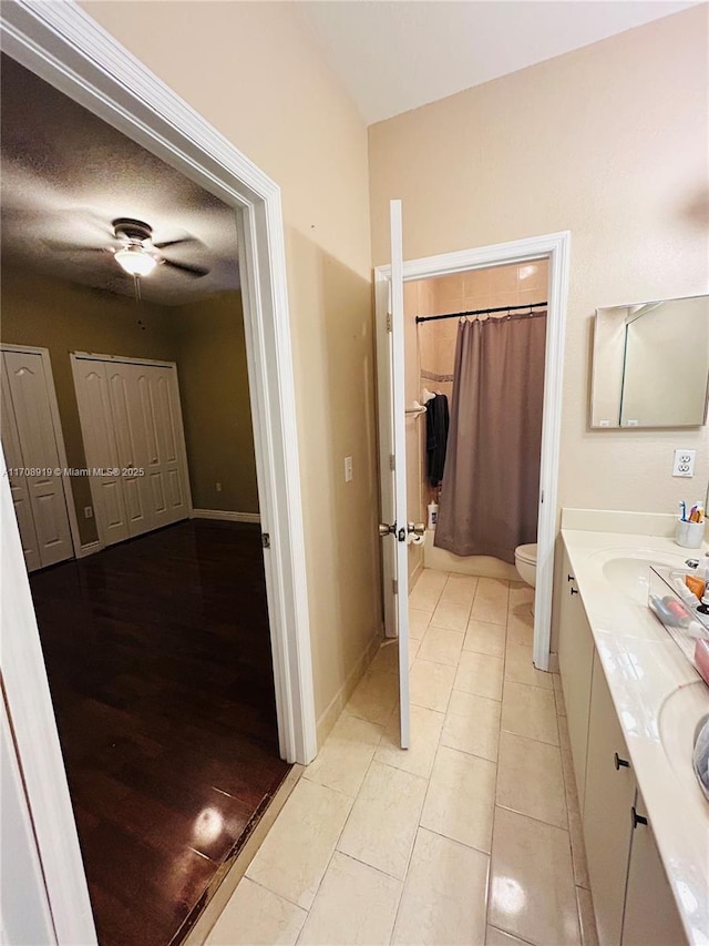 full bathroom featuring curtained shower, baseboards, toilet, tile patterned floors, and vanity