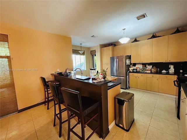 kitchen with dark countertops, visible vents, a peninsula, and freestanding refrigerator