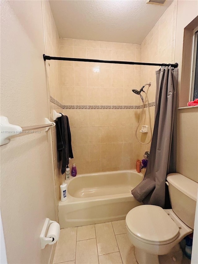 full bathroom featuring a textured ceiling, toilet, tile patterned flooring, and shower / bath combination with curtain