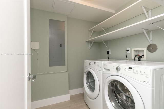 laundry room featuring light hardwood / wood-style floors, washing machine and dryer, and electric panel