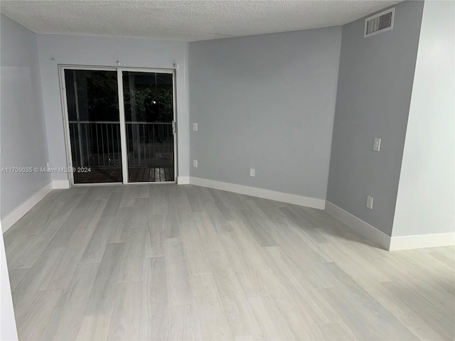 empty room featuring a textured ceiling and light wood-type flooring