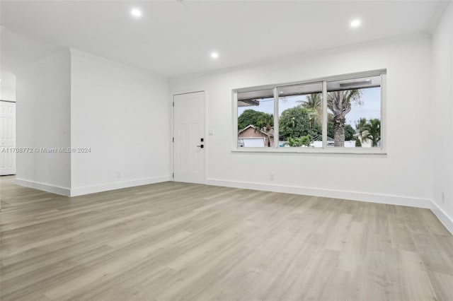 spare room featuring light wood-type flooring and crown molding