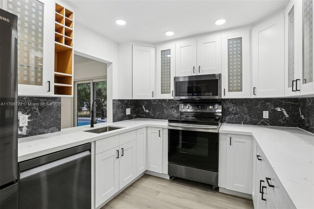 524 NW 7th Ct, Boynton Beach, FL 33426 - kitchen featuring appliances with stainless steel finishes, light stone counters, white cabinets, light wood-style floors, and glass insert cabinets
