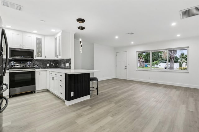 kitchen with white cabinets, decorative light fixtures, stainless steel appliances, and a breakfast bar